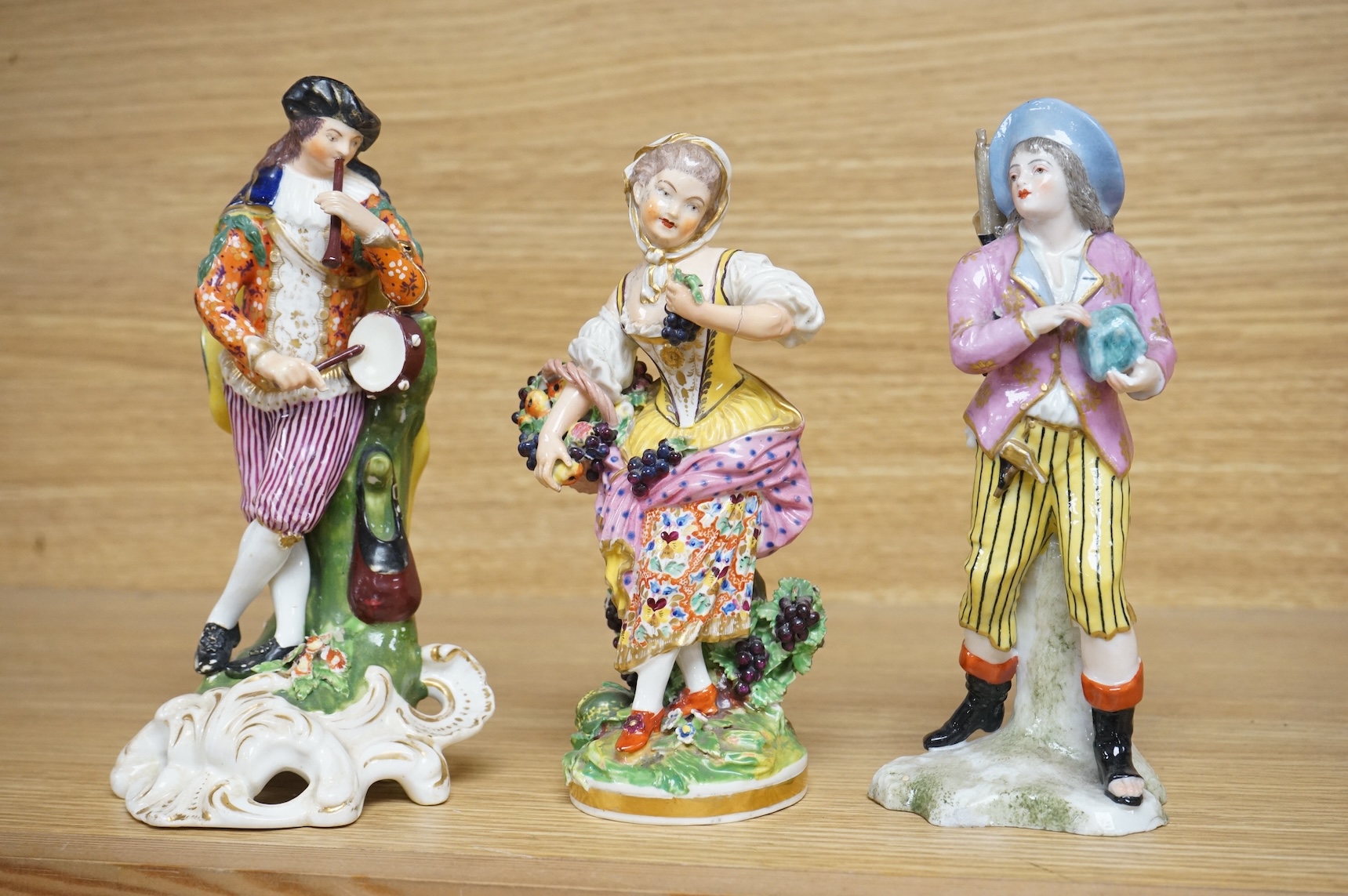 Three late 18th century Derby figures, a similar Derby figure of Summer, c.1810–30 and a Derby style figure of a street vendor, tallest 26cm high